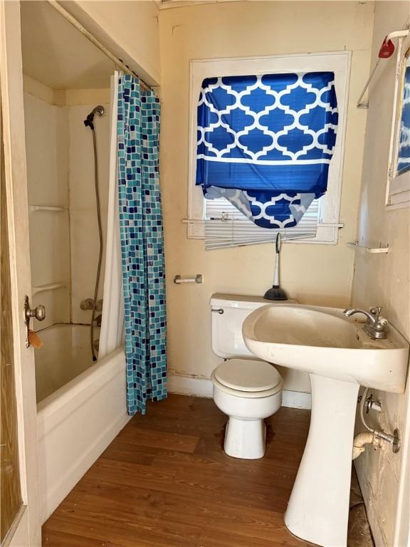 bathroom with hardwood / wood-style flooring, toilet, and shower / bath combo with shower curtain