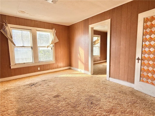 carpeted spare room featuring wood walls