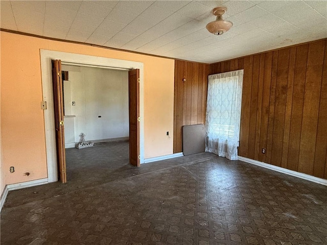 unfurnished room featuring crown molding and wood walls