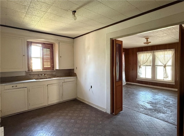 kitchen with white cabinetry, crown molding, and sink