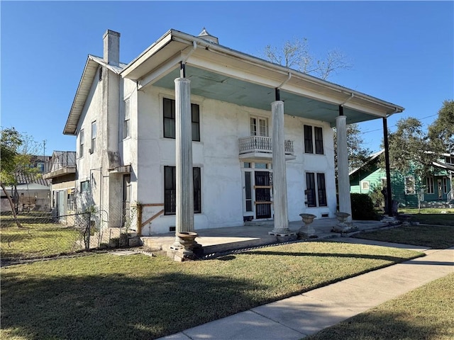 view of front of house with a front yard and a balcony