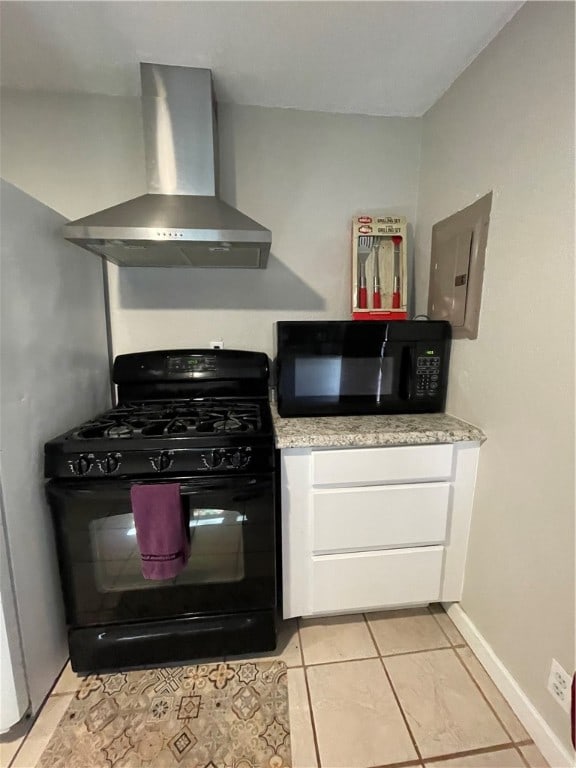 kitchen with wall chimney exhaust hood, black appliances, light tile patterned floors, electric panel, and white cabinetry