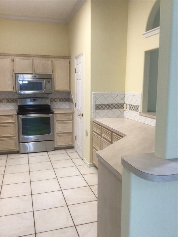 kitchen featuring light brown cabinets, decorative backsplash, stainless steel appliances, and light tile patterned flooring