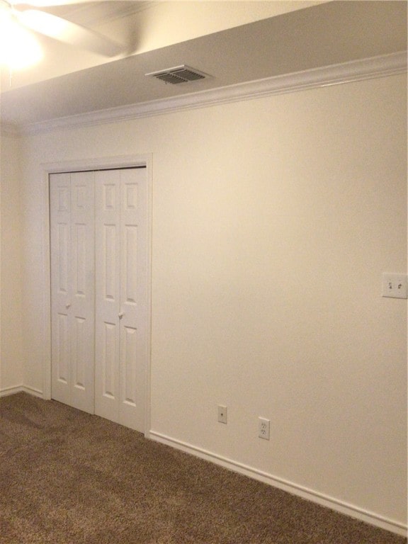 carpeted spare room featuring ceiling fan and crown molding