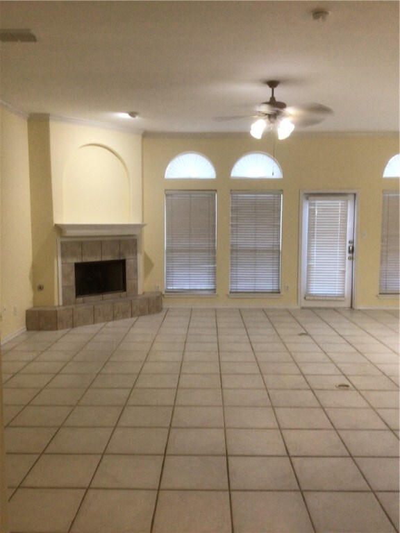 unfurnished living room with a fireplace, light tile patterned flooring, and ceiling fan