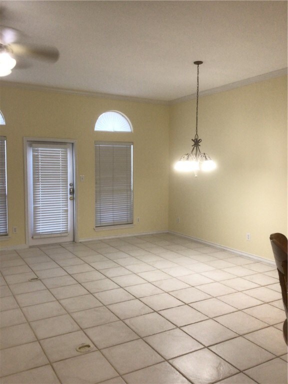 tiled spare room with ceiling fan and crown molding