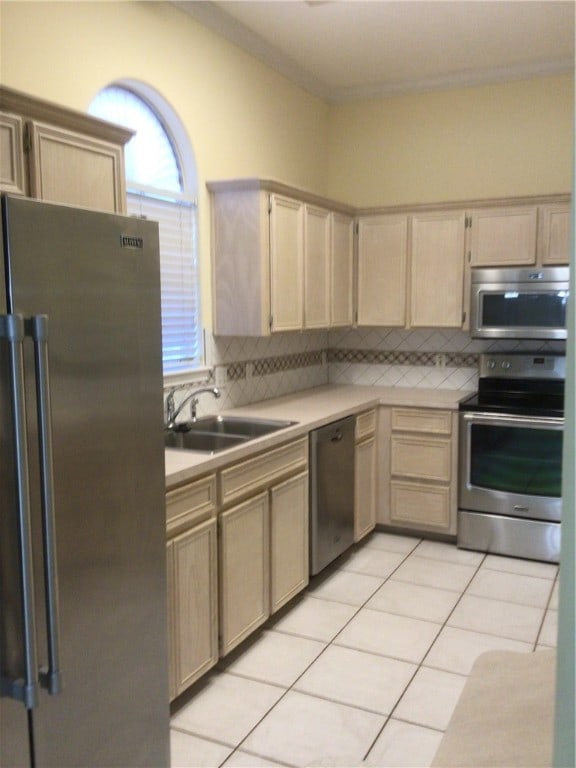 kitchen featuring backsplash, appliances with stainless steel finishes, light tile patterned floors, light brown cabinets, and sink