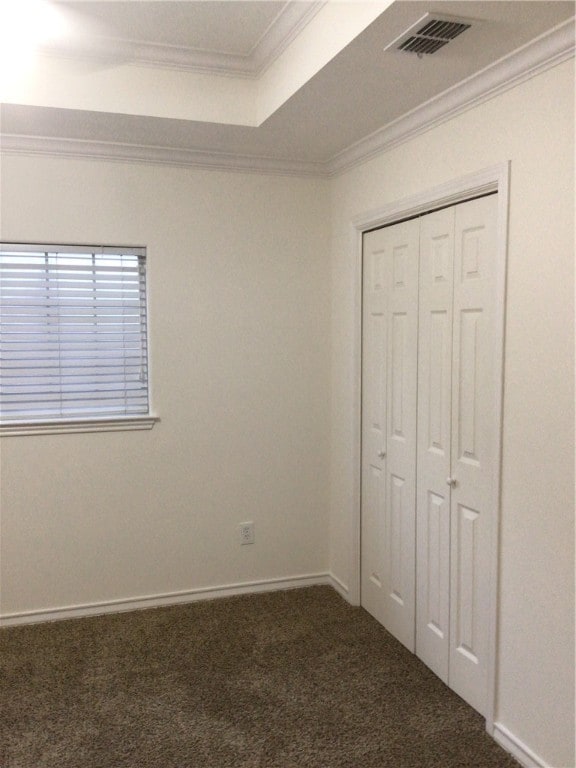 unfurnished bedroom featuring crown molding, a closet, and dark carpet