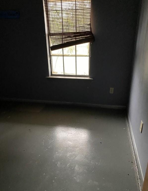 empty room featuring baseboards and concrete flooring