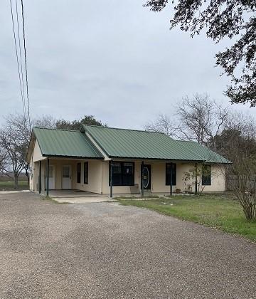 view of front of house with an attached carport, driveway, and metal roof