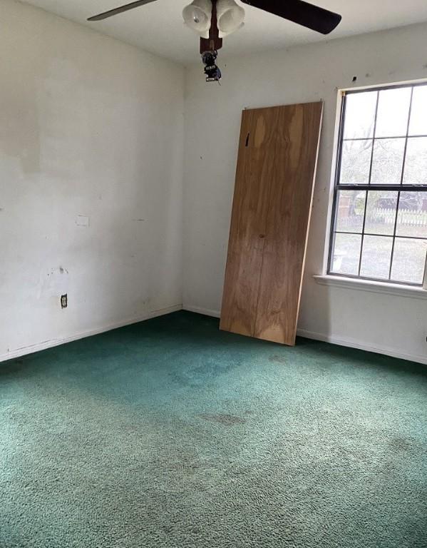 carpeted spare room featuring baseboards and ceiling fan