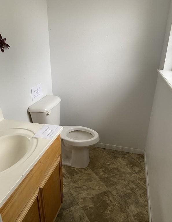 bathroom with baseboards, toilet, and vanity