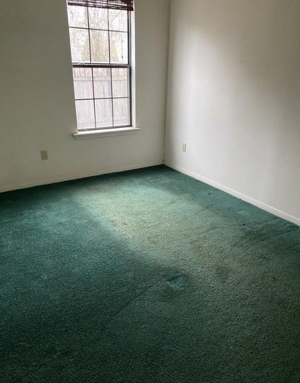 empty room featuring baseboards and dark colored carpet