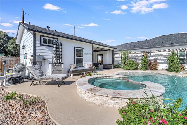 rear view of property with a swimming pool with hot tub and a patio