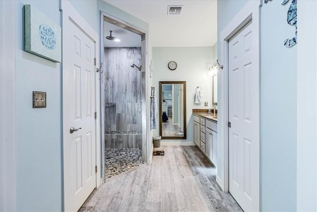 bathroom with a tile shower, vanity, and hardwood / wood-style flooring