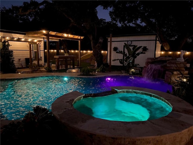 pool at night featuring an outdoor bar and an in ground hot tub