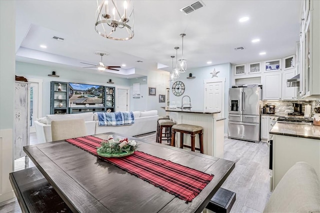 dining room with ceiling fan with notable chandelier and light hardwood / wood-style flooring