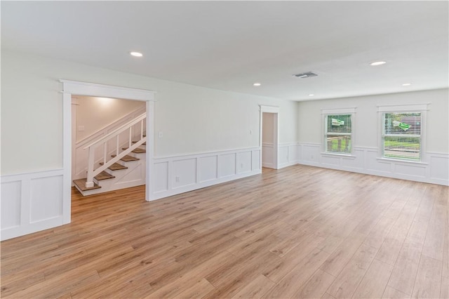 1101 6th St, Corpus Christi, TX 78404 - empty room featuring a decorative wall, wainscoting, stairs, light wood-type flooring, and recessed lighting