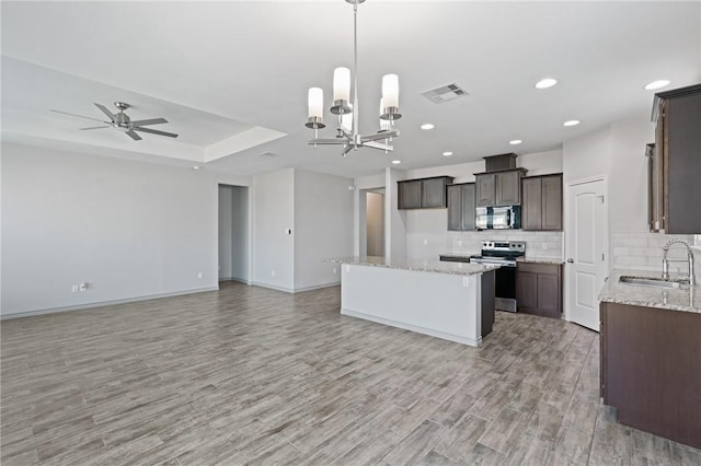 3406 Angelina St, Corpus Christi, TX 78414 - kitchen featuring appliances with stainless steel finishes, open floor plan, dark brown cabinetry, light wood-style floors, and decorative backsplash