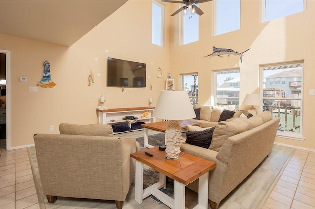 living room with ceiling fan, baseboards, and light tile patterned floors