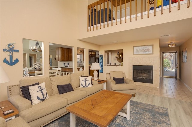 living room with a notable chandelier, a fireplace, wood finished floors, visible vents, and baseboards