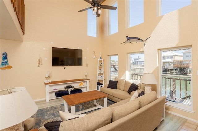 living area with wood finished floors, a ceiling fan, and baseboards