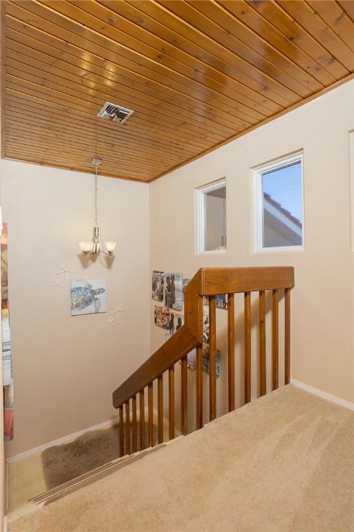 stairway featuring carpet, wood ceiling, baseboards, and a notable chandelier