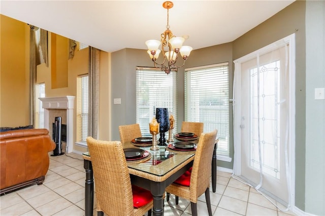 dining space featuring light tile patterned flooring, a notable chandelier, a fireplace, and baseboards