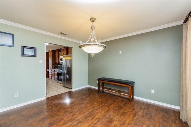 empty room featuring crown molding, wood finished floors, visible vents, and baseboards