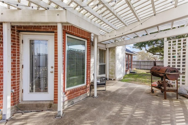 doorway to property featuring brick siding, a pergola, a patio, and fence