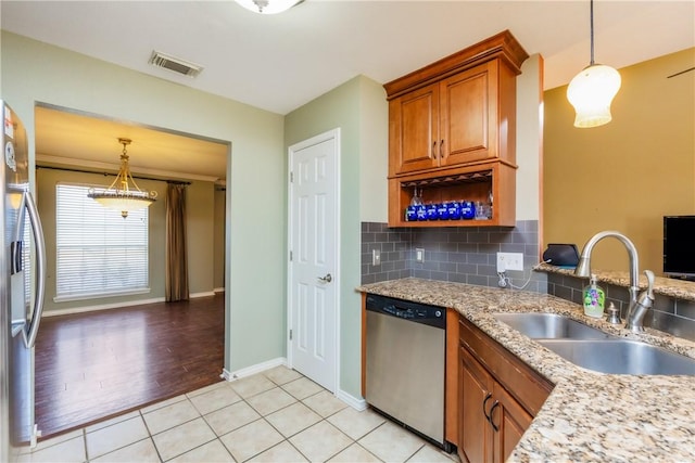 kitchen with brown cabinetry, visible vents, a sink, appliances with stainless steel finishes, and backsplash