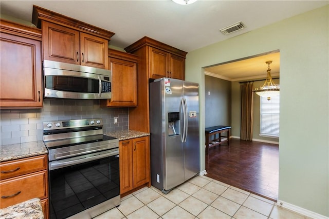 kitchen featuring stainless steel appliances, brown cabinets, tasteful backsplash, and visible vents