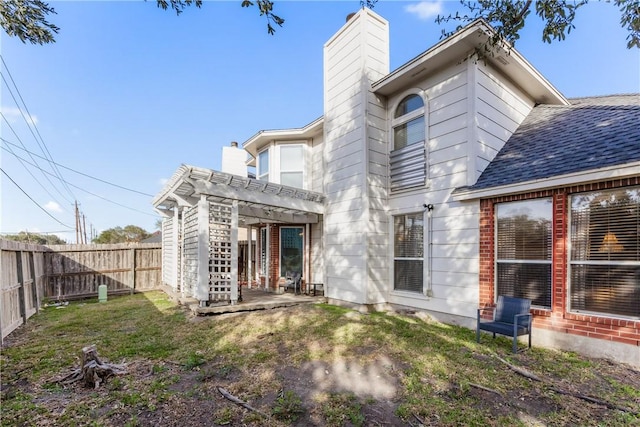 rear view of property with a patio, a fenced backyard, roof with shingles, and a chimney