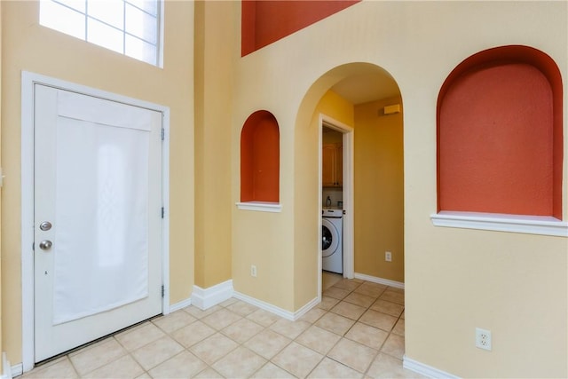 entrance foyer featuring washer / clothes dryer, baseboards, and light tile patterned floors