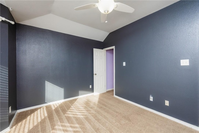 carpeted empty room with baseboards, a ceiling fan, and vaulted ceiling