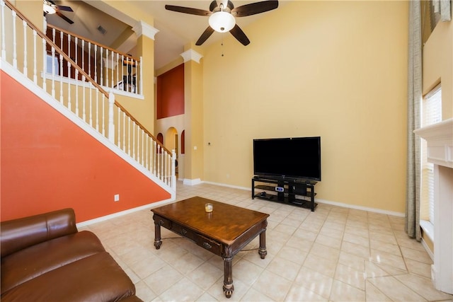 tiled living room with baseboards, stairs, a towering ceiling, arched walkways, and a ceiling fan