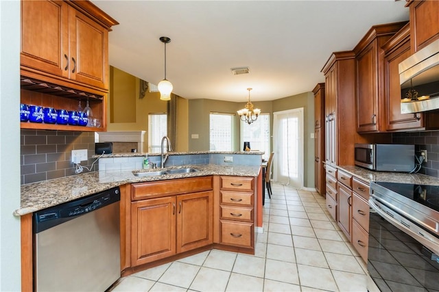 kitchen featuring brown cabinetry, visible vents, a peninsula, a sink, and stainless steel appliances