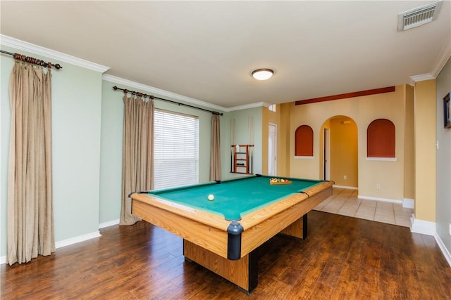 recreation room featuring wood finished floors, crown molding, arched walkways, and visible vents