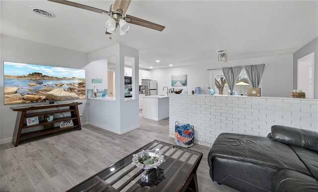 living room with ceiling fan, light hardwood / wood-style flooring, and sink