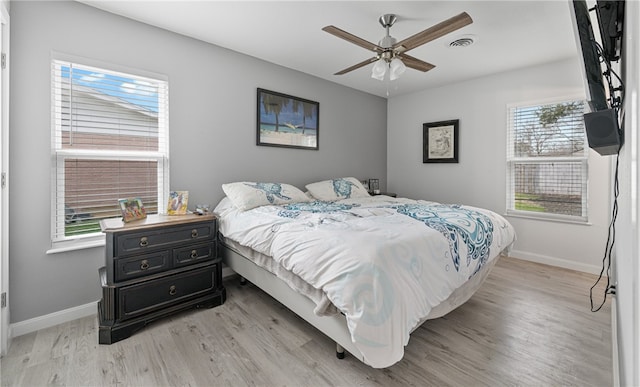 bedroom featuring light wood-type flooring, multiple windows, and ceiling fan