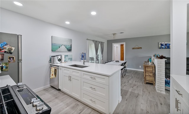 kitchen featuring sink, light hardwood / wood-style flooring, appliances with stainless steel finishes, white cabinetry, and kitchen peninsula