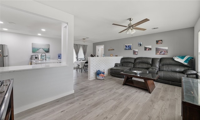 living room with light hardwood / wood-style floors, ceiling fan, and sink