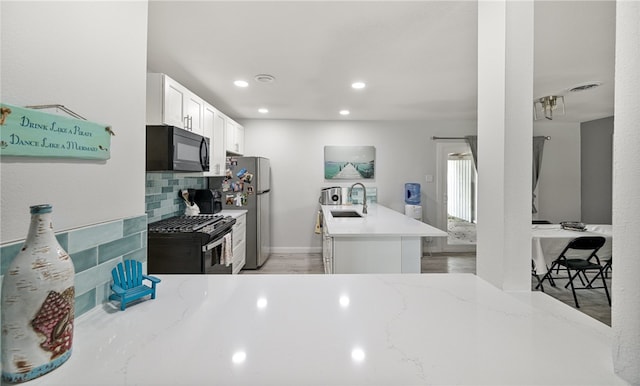 1411 Casa De Oro Dr, Corpus Christi, TX 78411 - kitchen with black appliances, tasteful backsplash, white cabinetry, light stone counters, and recessed lighting