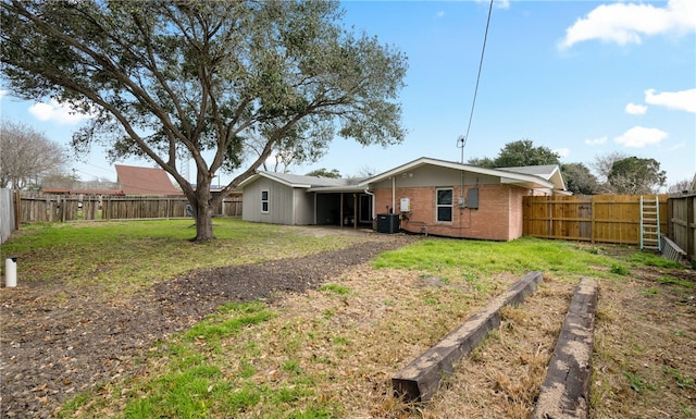 rear view of property with central AC and a yard