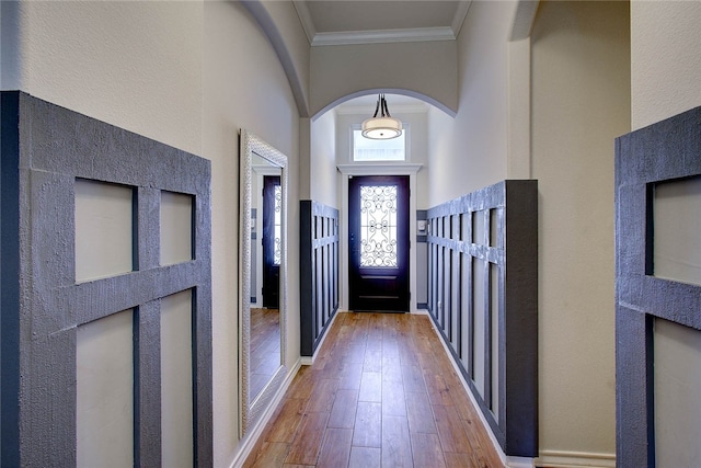 foyer with a towering ceiling, wood-type flooring, and crown molding