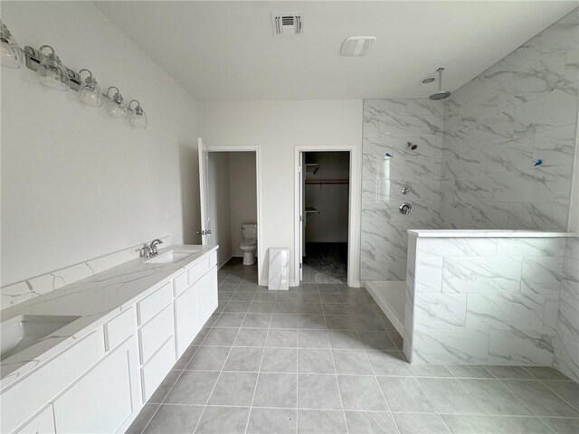 bathroom with a tile shower, vanity, and toilet