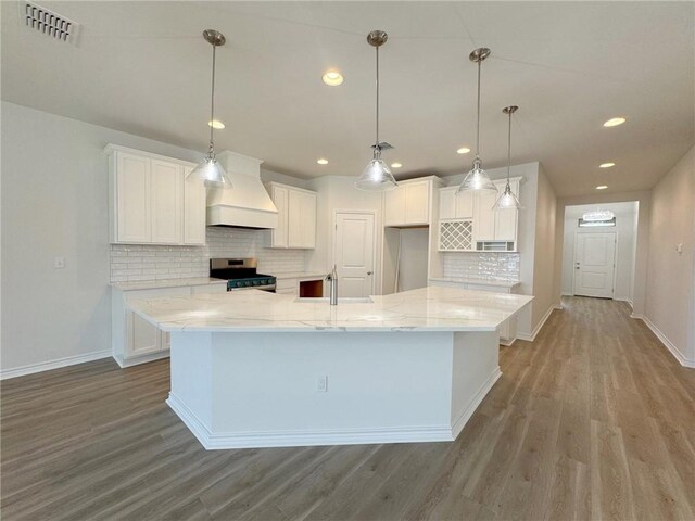 2550 Las Estrellas St, Corpus Christi, TX 78414 - kitchen with custom exhaust hood, stainless steel stove, wood finished floors, baseboards, and backsplash