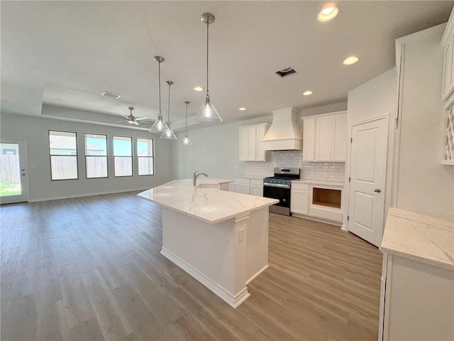 2550 Las Estrellas St, Corpus Christi, TX 78414 - kitchen with stainless steel gas range oven, wall chimney exhaust hood, backsplash, light wood finished floors, and a ceiling fan