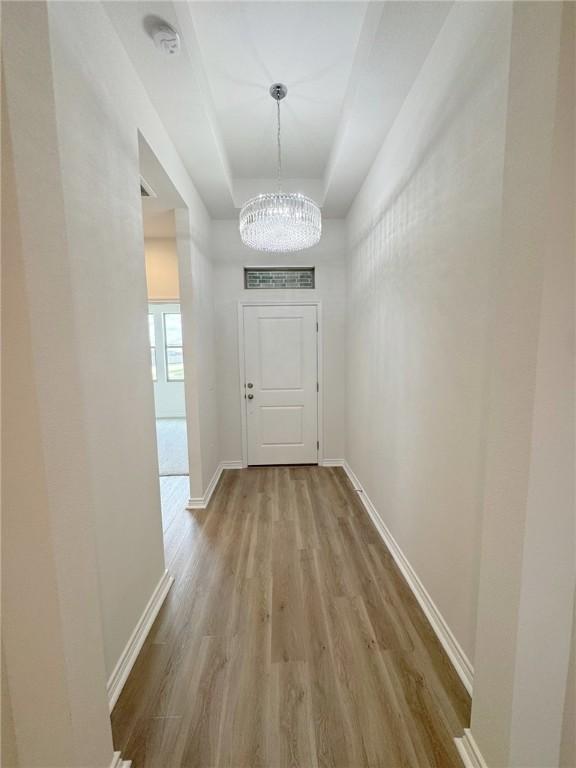 2550 Las Estrellas St, Corpus Christi, TX 78414 - entryway with wood finished floors, a chandelier, a tray ceiling, and baseboards