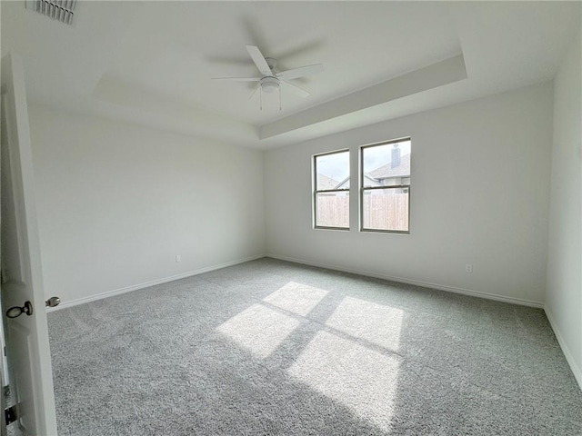 carpeted empty room with a tray ceiling and ceiling fan